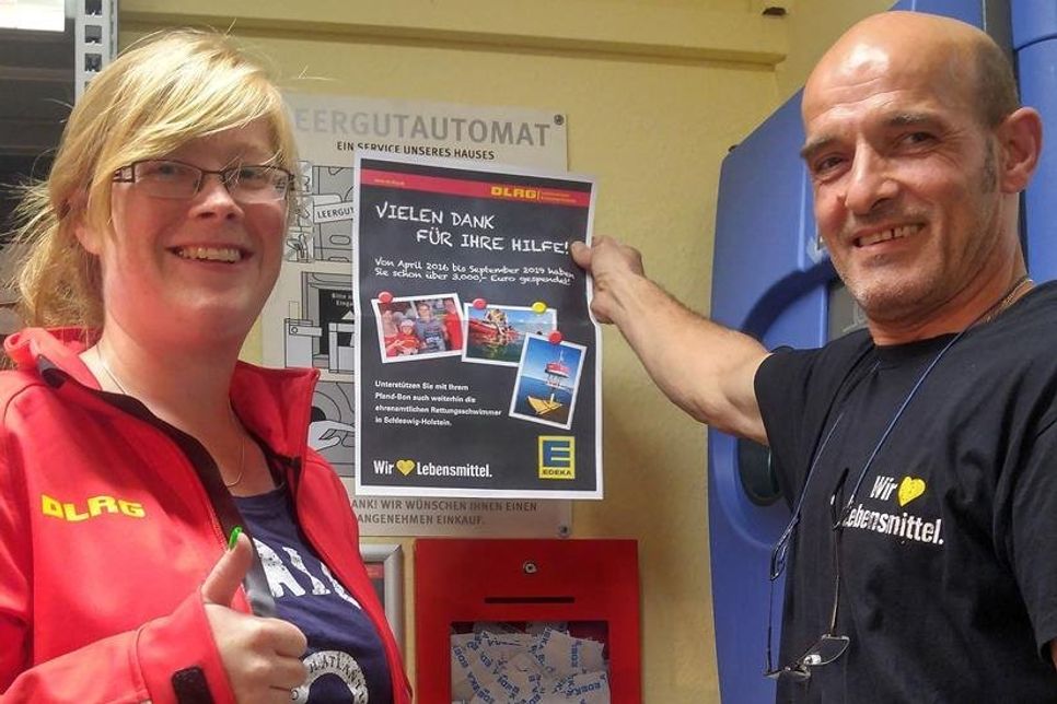 Maja Schikorr (DLRG Grömitz e.V.) montiert gemeinsam mit der EDEKA-Crew ein neues Dankesplakat in der Wicheldorfer Straße: 3.000 Euro