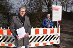 Hansjörg Wittern, stellvertretender Pressesprecher der Hansestadt Lübeck, und Uwe Kirchhoff, Kurdirektor von Travemünde, präsentieren der Presse die Warnbarken mit dem neuen Hinweisschild auf dem Wanderweg der Brodtener Steilküste.