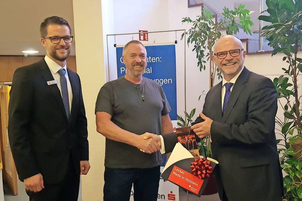 Joachim Wallmeroth (re.), stellvertretender Vorstandsvorsitzender der Sparkasse Holstein, und Tim Dummer (lks.), Leiter der Filiale Neustadt der Sparkasse Holstein, überreichten den Gewinn an Erwin Bruns.