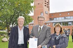 Christian Dwars (Mitte), stellvertretender Bürgermeister der Gemeinde Scharbeutz, erhält von Sandra Redmann und Hermann Schultz Plakette und Urkunde, im Hintergrund der Turm mit den Installationen für die Fledermäuse. (Foto: Eknad)