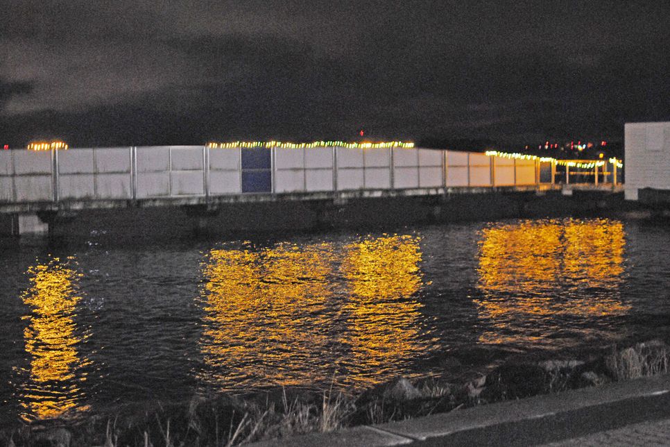 Weihnachtliche Beleuchtung spiegelt sich im Wasser der Kieler Förde, taucht die Seebadeanstalt in malerisches Licht.