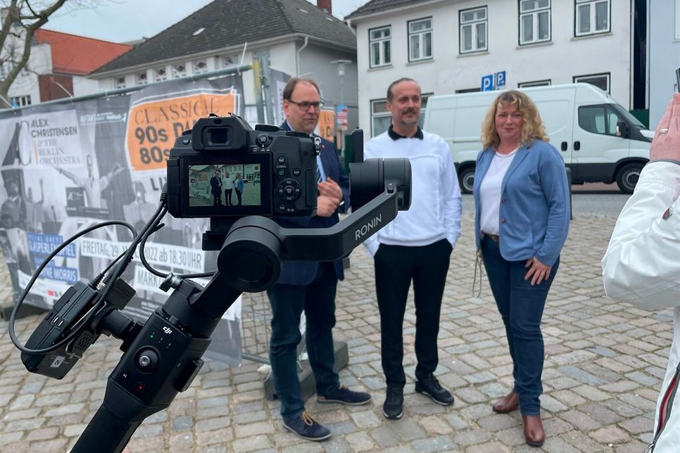 Bürgermeister Mirko Spieckermann (lks.) , Alex Christensen und Kuratoriumsvorsitzende des Folklorefestivals Barbara Helbach bei den Filmaufnahmen.