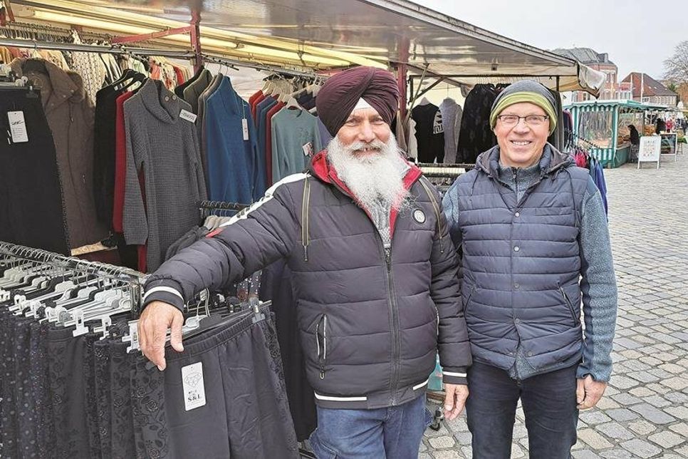 Mit den meisten Händlern ist Mathias Voigt (rechts) per Du, so auch mit Textilverkäufer Sarwan Bahia, der 1997 auf dem hiesigen Wochenmarkt in die Selbstständigkeit gestartet ist.