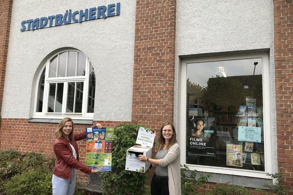 Nachhaltigkeitsmanagerin Lina Koop und Mitarbeiterin der Stadtbücherei Laura Dorittke (v. lks.) mit der Handysammelbox.
