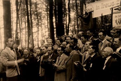 Das Foto aus meiner alten Bildersammlung zeigt Erwin Jamrosy 1956 anlässlich des 100-jährigen Jubiläums der „Gleschendorfer Liedertafel von 1856“ mit einem Auftritt dieses Chores im Gleschendorfer Pastoratswald an der Schwartau. Auch Gastchöre nahmen teil.