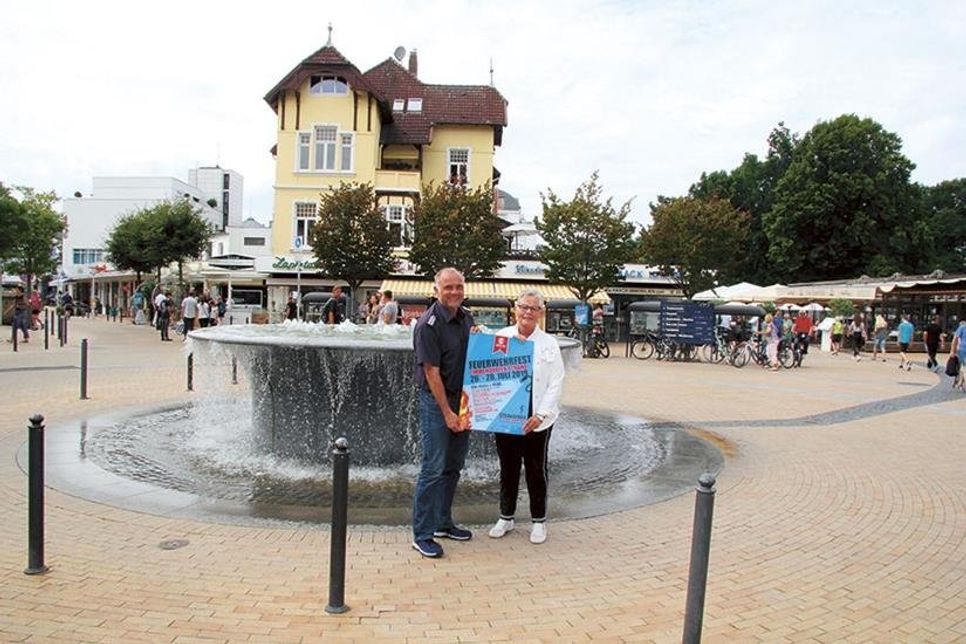 Dirk Scharbau (Feuerwehr Timmendorfer Strand) und Rotraut Schwarz (Strand Promotion) präsentieren das Plakat zum diesjährigen Feuerwehrfest. Foto: VA/hfr