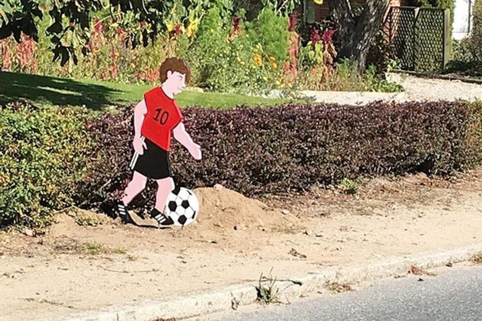 Ein toller Hingucker und eine gelungene Ermahnung: Mitten im Dorf spielt ein Junge Fußball.