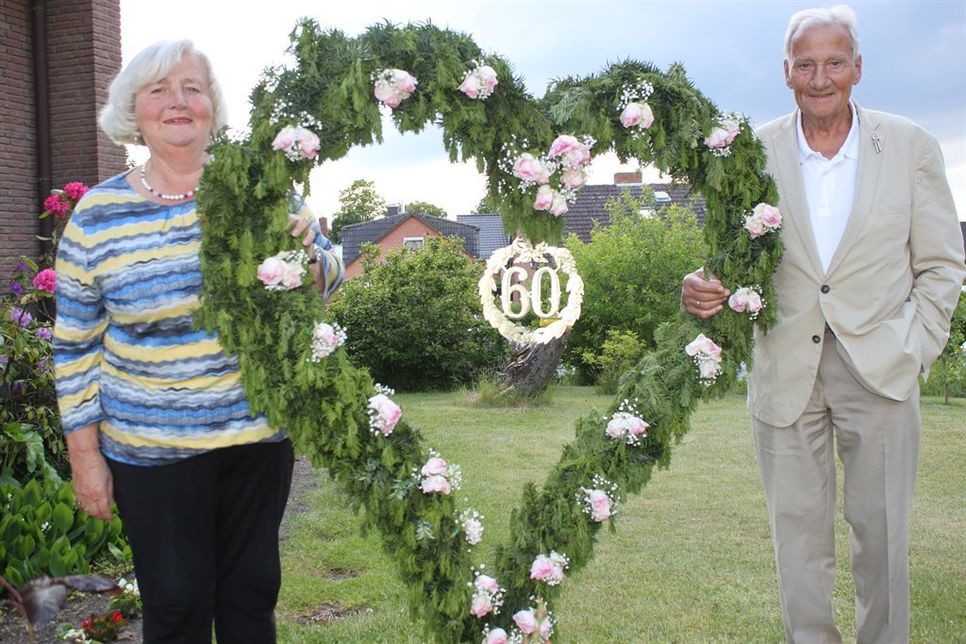 Das Ehepaar Schröder im heimischen Garten mit einem Kranz in Herzform.