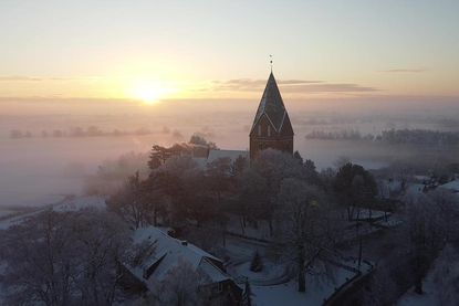 Dieses bezaubernde Drohnenfoto von Pastor Friedemann Holmer aus Altenkrempe zeigt einen stillen Wintermorgen, an dem sich die Sonne sanft durch den Nebel schiebt und die Basilika in warmes Licht taucht.