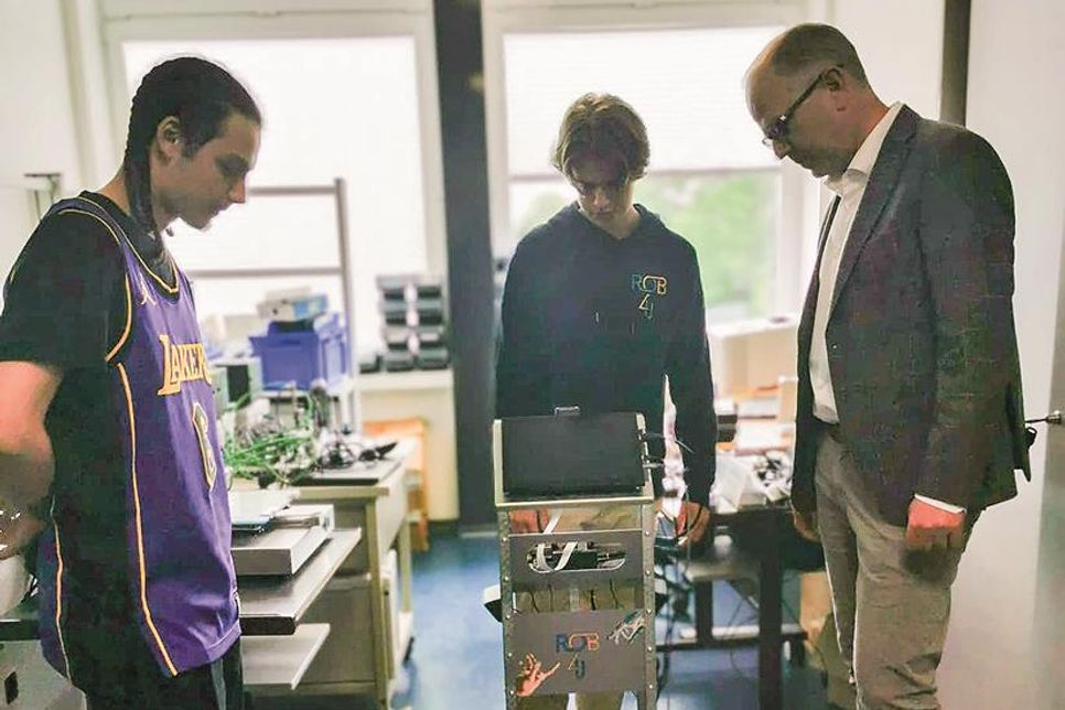 Die Schüler Tom Kröger und Richard Luksik Stellen dem Schulleiter Christoph Salweski den Begrüßungsroboter vor.