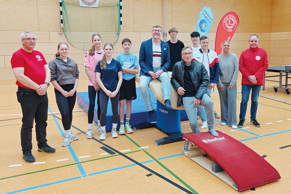 Offizielle Übergabe der neuen Sportgeräte in der 3-Felder-Sporthalle: Schülerinnen und Schüler der achten Klassen freuen sich darüber mit Schulleiterin Esther Passig (2.v.re.), NTSV-Vorsitzenden Andreas Block (rechts), Sportwart Detlef Ossyra (links), Bürgermeister Sven Partheil-Böhnke (in der Mitte sitzend), Gemeindevertreter Dr. Axel Michael Unger (SPD) und Dennis Schlehahn (Fachdienst Bildung, Sport und Familienangelegenheiten, 3.v.re.).