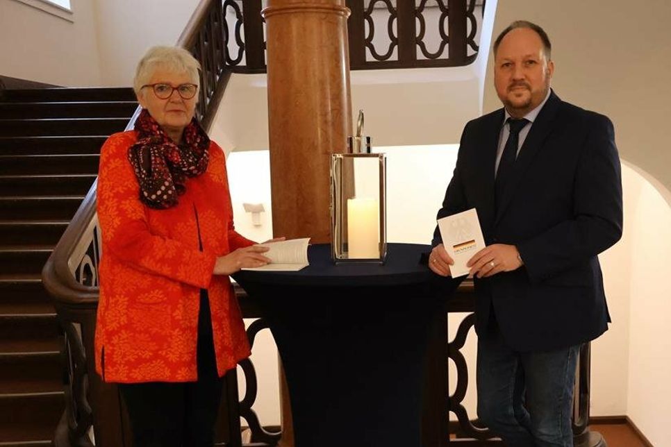Kreispräsidentin Petra Kirner und Landrat Timo Gaarz halten symbolisch das Grundgesetz in der Hand.