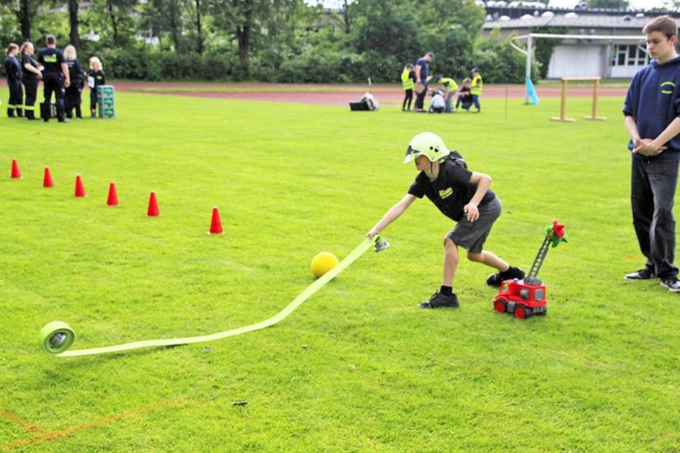 Ein junger Nachwuchsfeuerwehrmann rollt den Schlauch fachgerecht aus.