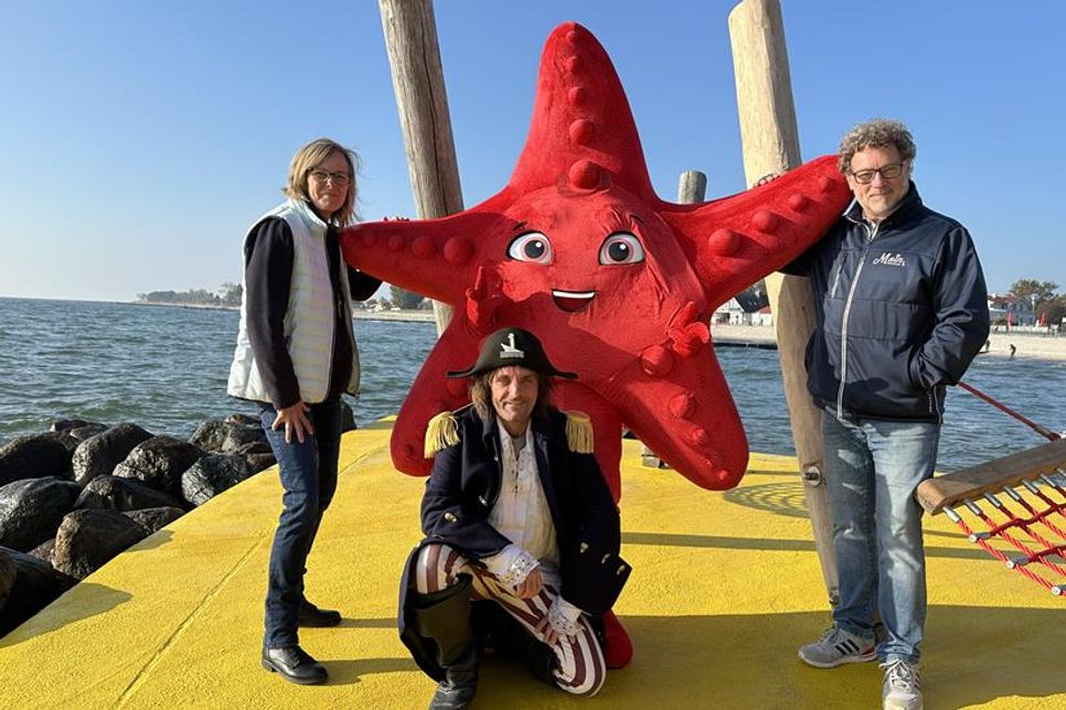 Wybke Schmidt (lks.), erste Vorsitzende des Tourismusvereins Kellenhusen, freut sich, den kleinen Seestern begrüßen und an Tourismusleiter Raymond Kiesbye (re.) übergeben zu können.