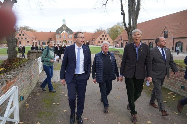 Ministerpräsident Daniel Günther (lks.), Dr. Constantin Stahlberg (2. v. re.) und Landrat Timo Gaarz (re.) beim Rundgang auf dem historischen Gutshof.