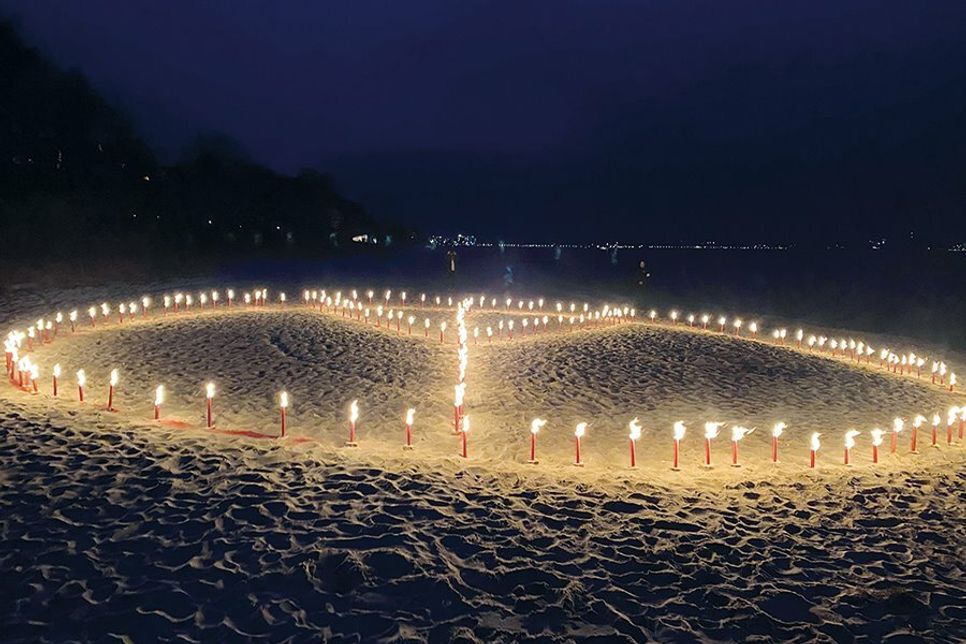 Die Teilnehmer steckten Hunderte Fackeln in den Sand und bildeten damit das Friedenszeichen.