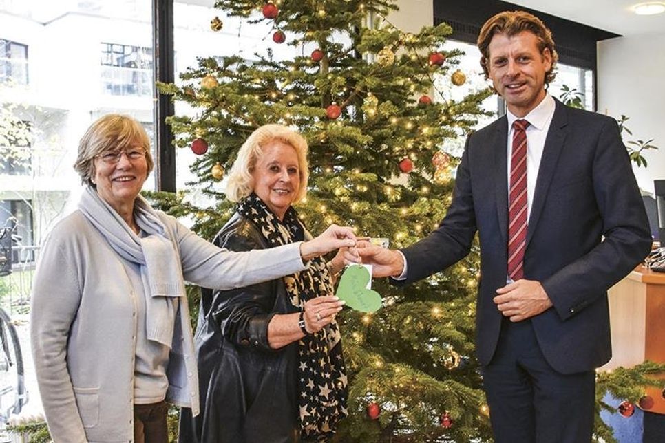 Barbara Bergmann, Vorsitzende von „Kinderherz e.V.“ (links), Christine Gebauer, Unterstützerin der „Sternenbrücke Hamburg“, und Bürgermeister Robert Wagner vor dem „Weihnachts-Wunschbaum“ im Timmendorfer Rathaus. (Foto: René Kleinschmidt)