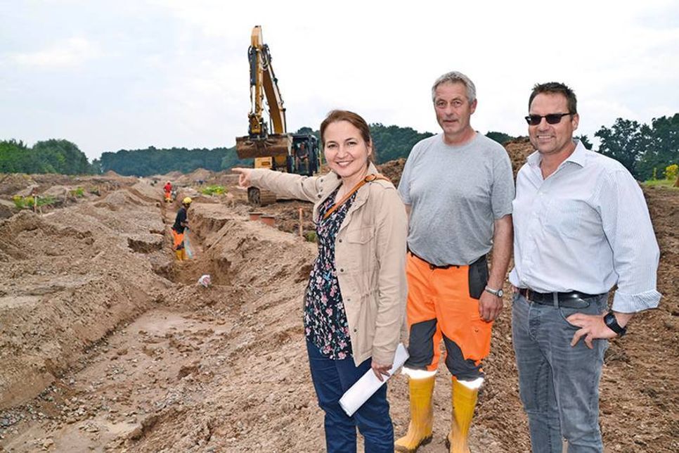 Bürgermeisterin Hatice Kara, Schachtmeister Armin Kortz und Tiefbau-Ingenieur Michael Hasselberg vom Bauamt machen sich vor Ort ein Bild von den Erschließungsarbeiten für das Neubaugebiet. (Foto: René Kleinschmidt)