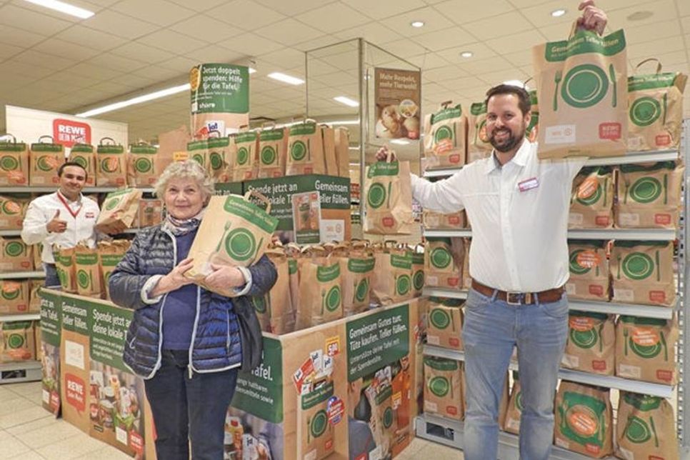 Ingeborg Schläfke freut sich über mehr als 1000 Tüten für die Tafel, die Alexander Meier (REWE-Marktleiter Eutin Industriestraße) und Malte Rehmke (REWE-Marktleiter Malente) symbolisch übergaben.