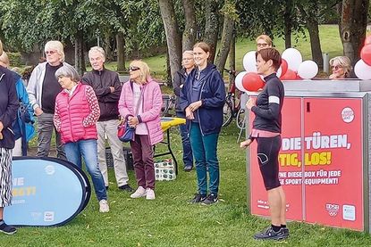 Interessierte verfolgen bei der Eröffnungsfeier die Vorstellung der Materialien. Anja Künzel vom Bereich „Schule und Sport“ (Hansestadt Lübeck) steht vor der neuen Sportbox, links neben ihr Karin Schulze Kersting, Vorsitzende von „Freizeit und Aktiv e.V.“.