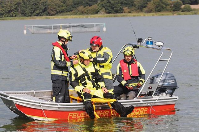 Eine Person wird mit dem Spineboard ins Boot gehebelt.