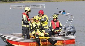 Eine Person wird mit dem Spineboard ins Boot gehebelt.