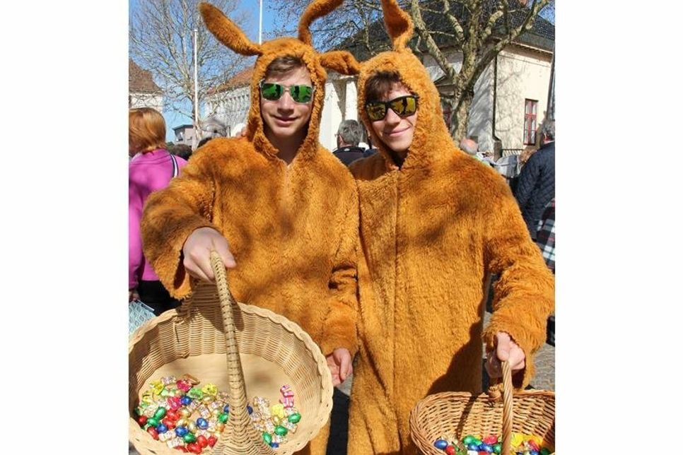 Großen Osterhasen verteilen Süßigkeiten an die Kinder.