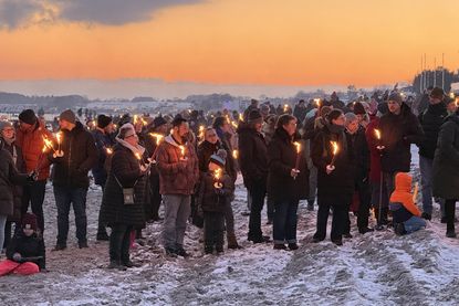 Ein Meer aus Fackeln im Abendrot: Tausende versammeln sich am Strand, um gemeinsam das traditionelle Feuer zu erleben.