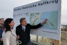 Bettina Schäfer, Bürgermeisterin der Gemeinde Scharbeutz, schaut sich mit Minister Dr. Bernd Buchholz die Bau-Tafel der neuen Seebrücke an. (Foto: René Kleinschmidt)