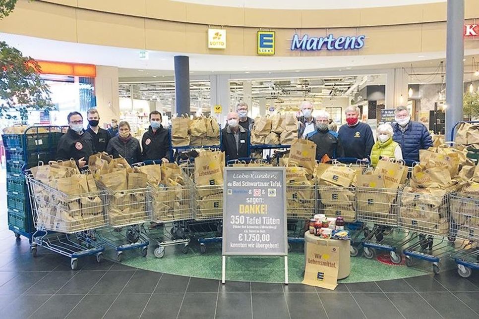 Die Arbeit ist geschafft: Zufrieden stehen die sieben Mitglieder des Lions Clubs und des Round Tabel vor den gepackten 250 Tüten für die Tafel. Links im Bild vier Mitarbeiter der Tafel Bad Schwartau, bereit zum Verladen der Spenden.