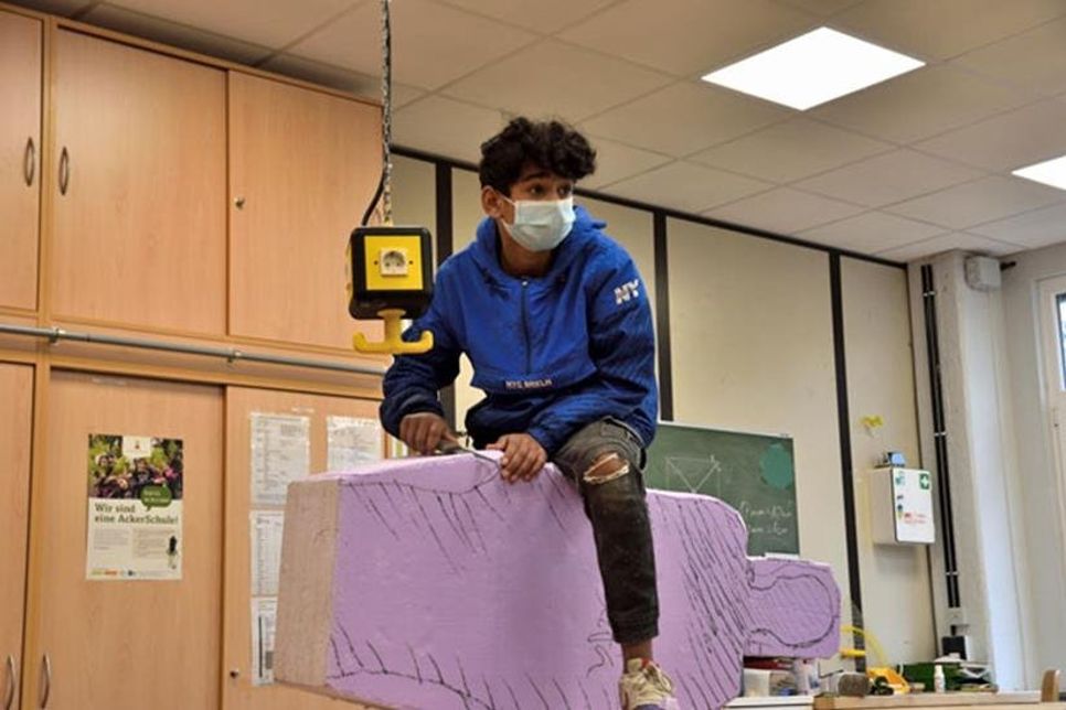 Mustafa hat sich kurzerhand rittlings auf seinen Hartschaumblock gesetzt, um die Arbeit mit der Feile besser in den Griff zu bekommen.