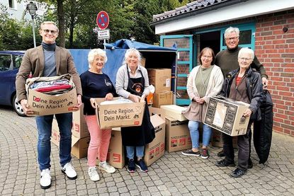 Christoph Kressin (li.) und Bert Muller (hi.re.) vom Lions Club Lübecker Bucht bei der Übergabe der Kleiderspende an die ehrenamtlichen Helferinnen der Tafel, Heike Hauch, Rosi Krug-Stroh (3.v.li.), Andrea Grose und Helga Herrmann (re.).
