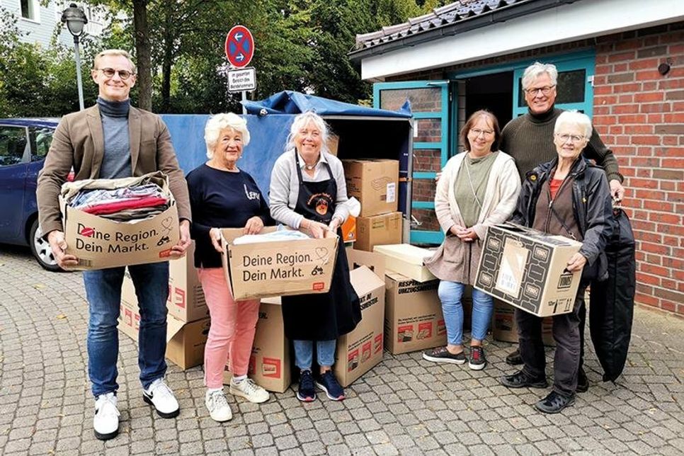 Christoph Kressin (li.) und Bert Muller (hi.re.) vom Lions Club Lübecker Bucht bei der Übergabe der Kleiderspende an die ehrenamtlichen Helferinnen der Tafel, Heike Hauch, Rosi Krug-Stroh (3.v.li.), Andrea Grose und Helga Herrmann (re.).