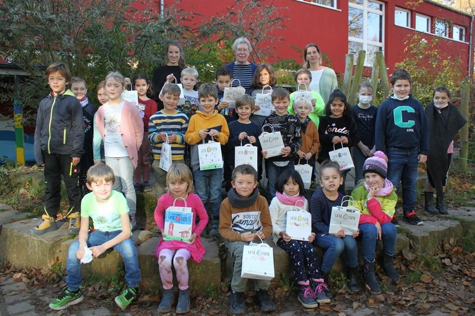 Die Grundschüler präsentierten stolz ihre Lesetüten, die Gabriela Bendfeldt (hi. Mitte) übergab. Ohne Lesetüten sind die Zweitklässler auf dem Foto, die bei der Verteilung halfen.