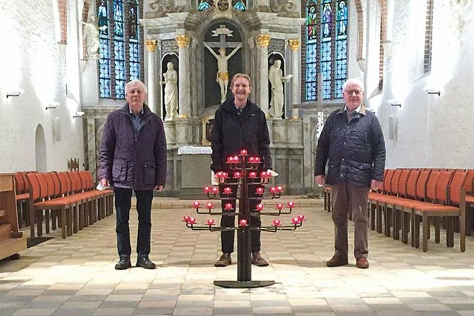 (v.l.) Hütedienstleiter Klaus Kasper, Pastor Andreas Gruben und Hüter Gerd Ernst freuen sich über den neuen Kerzenständer in der St.-Johannis-Kirche.
