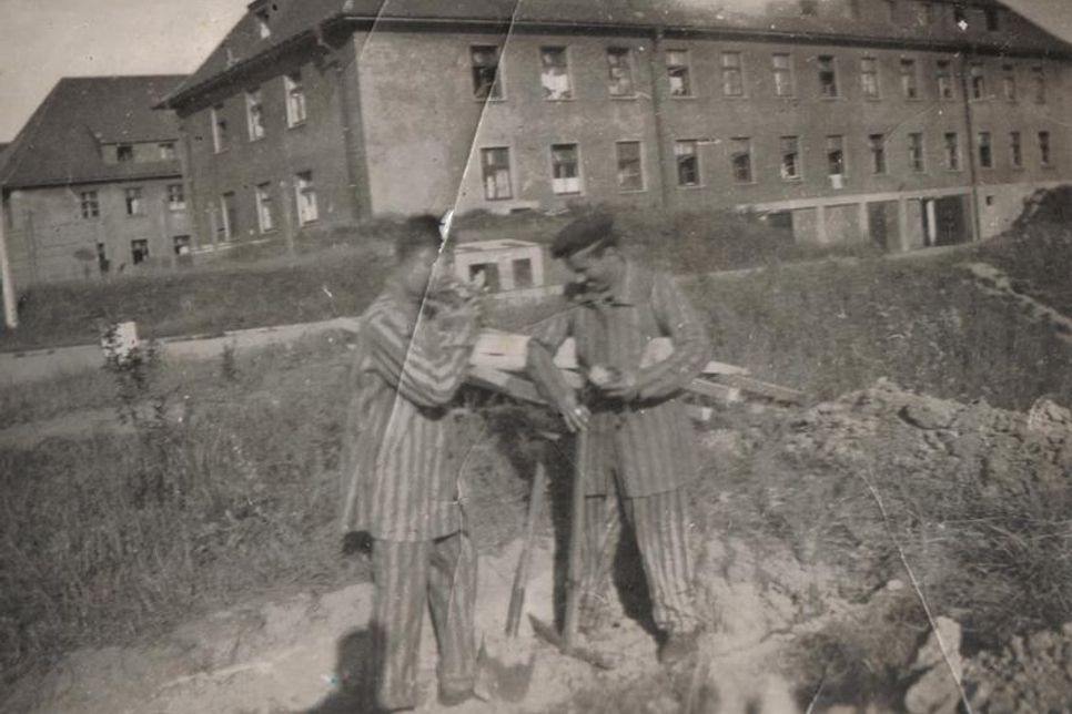 Zwei junge Griechen vor den ehemaligen Marinekasernen auf dem Wieksberg, die in der Nachkriegszeit als DP-Lager genutzt wurden. Die beiden Männer tragen Häftlingskleidung des KZ Neuengamme. Sie waren kurz zuvor aus dem Hamburger Konzentrationslager in die Lübecker Bucht auf die Cap Arcona verschleppt worden und überlebten die Schiffskatastrophe. Foto vermutlich von Mai 1945. (Bildquelle: Kostas Chalemos, Griechenland)