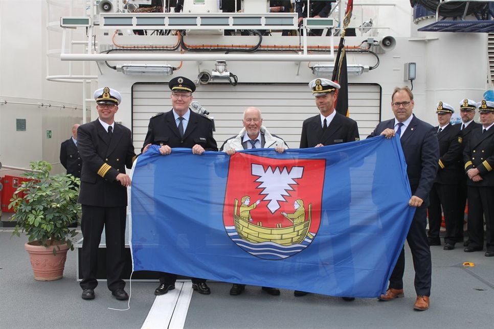 Bürgervorsteher Sönke Sela (Mi.) und Bürgermeister Mirko Spieckermann (re.) übergaben die Flagge der Stadt Neustadt an die Besatzung der „Potsdam“.
