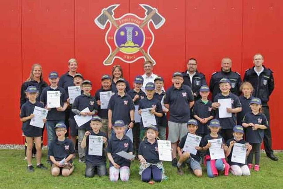 Die „Flammen“-Kinder mit ihren Urkunden. - Hintere Reihe von links: Monika Schröder, Kinderfeuerwehr-Wartinnen Nadine Cassel und Angelika Schlichting, Gemeindewehrführer Rolf Müller, Ortswehrführer Dirk Martens, stellv. Ortswehrführer Mike Cassel und Jugendfeuerwehrwart Christian Manara.