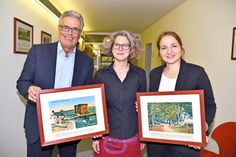 Archivarin Melanie Zühlke (Mitte), Bürgermeisterin Hatice Kara und Bürgermeister Volker Owerien mit zwei Bildern aus der Dauerausstellung „Stranderwachen“ im Timmendorfer Rathaus. (Foto: René Kleinschmidt)