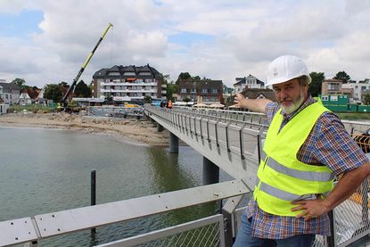 Bauoberleiter Matthias Franke vom Planungsbüro SWUP GmbH Berlin zeigt auf die entstehende Treppenanlage/Tribüne am Seebrückenvorplatz in Haffkrug.