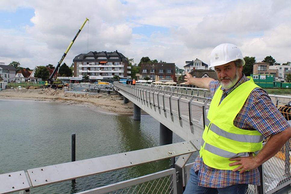 Bauoberleiter Matthias Franke vom Planungsbüro SWUP GmbH Berlin zeigt auf die entstehende Treppenanlage/Tribüne am Seebrückenvorplatz in Haffkrug.
