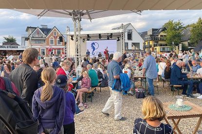 Gute Laune bei verschiedenen Getränken und Speisen vor der Hafenbühne, auf der diverse Live-Acts auftreten.