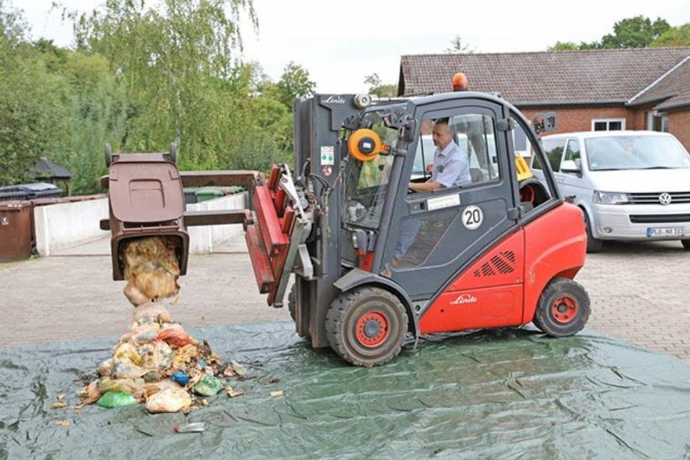 Plön (hl). Rund 14000 Tonnen Biomüll werden jährlich im Kreis Plön eingesammelt - doch die Qualität lässt zu Wünschen übrig: Noch immer verirren sich Plastiktüten oder Restmüll oder sogar Joghurtbecher in die braune Tonne - mal aus Unwissenheit der Bürger:innen, mal aus Ignoranz. Im September fanden deshalb in ganz Schleswig-Holstein unter Schirmherrschaft von Umweltminister Jan-Philipp Albrecht Aktionstage zum Thema Bioabfall statt: die Abfallwirtschaft des Kreises Plön beteiligte sich daran und zeigte anhand von Beispielen, wie die braune Tonne richtig befüllt wird. Die erste braune Tonne, die exemplarisch ausgekippt wird, ist das perfekte schlechte Beispiel: Die Abfälle in der Tonne sind verpackt in Plastiktüten, eine leere Spülmittelflasche aus Plastik fällt zwischen zwei Müllbeuteln heraus und am Ende folgt ein übelriechender Schwall Flüssigkeit.  Dabei ist zumindest die Verwendung von Plastiktüten oft gar keine böse Absicht: „Das Problem ist, das kompostierbar nicht immer gleich