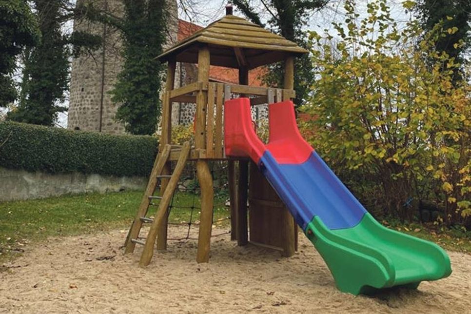 Der bunte Kletterturm ist bei den Kindern sehr beliebt. Im Hintergrund sieht man die Feldsteinkirche St. Johannis.