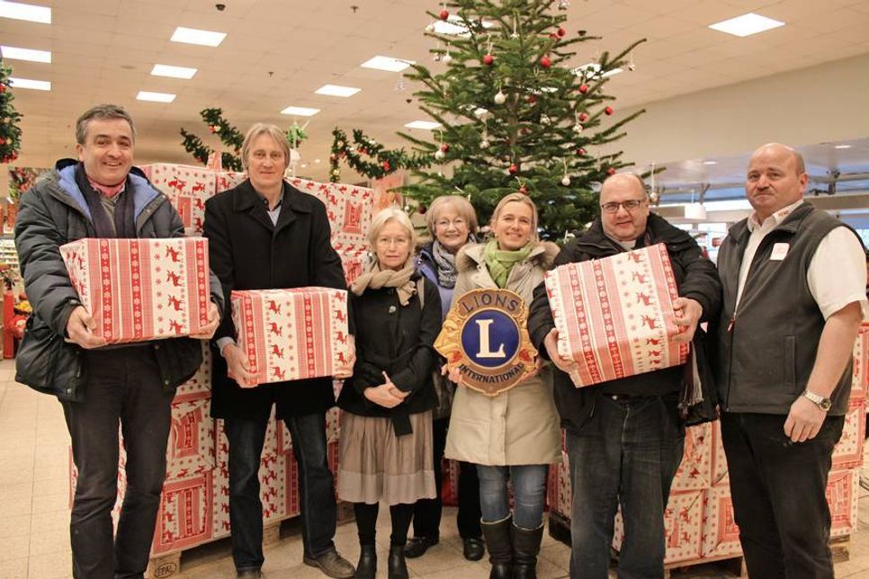 Pastor Torsten Marienhagen, Pastor Jens Rathjen, Monika Rieth und Marion Esser vom Kinderschutzbund, Lions-Organisatorin Juliana Stolz, Pastor Andreas Hasse und Marktleiter Jörg Flad (v. lks.) mit den Paketen, die mit weihnachtlichen Leckereien versehen wurden.