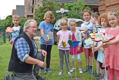 Die Erstklässler haben, zusammen mit Klaus Mende (li.), aus Holz Bienen, Blumen, Vögel und Schmetterlinge ausgesägt, bemalt und auf Metallstangen gesetzt.