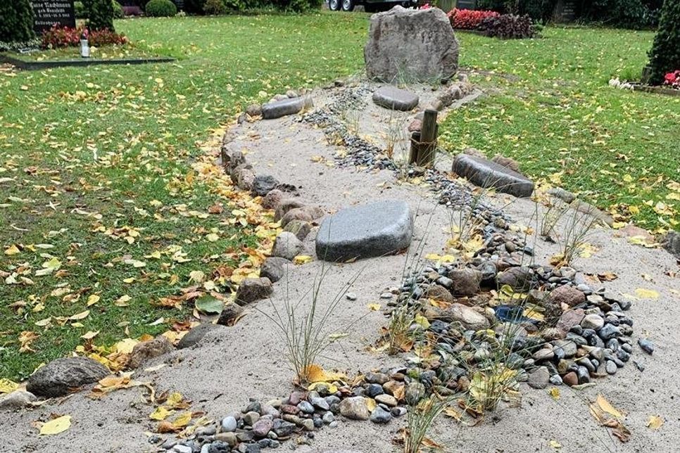 Mehrere Grabplatten liegen zwischen Strandhafer und Seesand eingebettet.