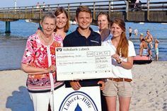 Große Freude bei der Spendenübergabe am Scharbeutzer Strand (von links nach rechts): Heidemarie Vesper (Lübeck-Hilfe für krebskranke Kinder e.V.), Sonja Zastrow (TALB) und Falko Rieper sowie Janina Pohlmann und Lena Röhrs vom Projektteam „Abenteuer-Fußballwoche“. (Foto: TALB)