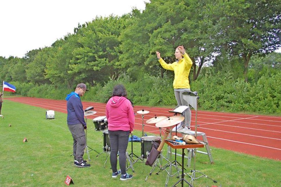 Lagebesprechung auf dem Sportplatz. Das neue Musikprogramm braucht noch die passende Choreographie. Madline Lentins (auf der Trittleiter) berät sich mit Bandmitgliedern.