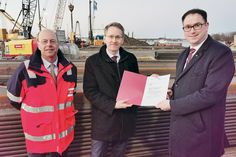Schleswig-Holsteins Ministerpräsident Daniel Günther übergibt den Förderbescheid an Lübecks Bürgermeister Jan Lindenau (rechts), auch sehr zur Freude von LHG-Chef Sebastian Jürgens (links).